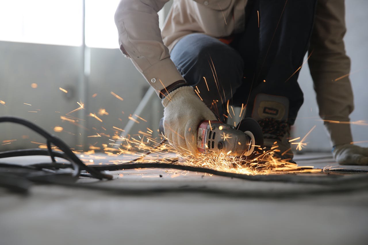 about-us A skilled industrial worker uses a grinder creating a burst of sparks indoors.