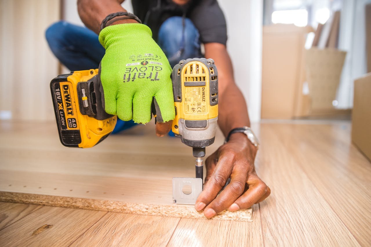 why-choose-us Man using a power drill for home improvement on a wooden floor with precision.